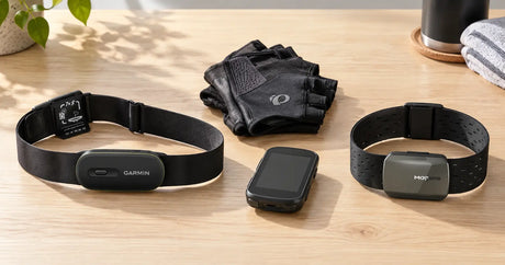 A Garmin HRM 600 chest strap and a Magene H803 optical armband side by side on a wooden table